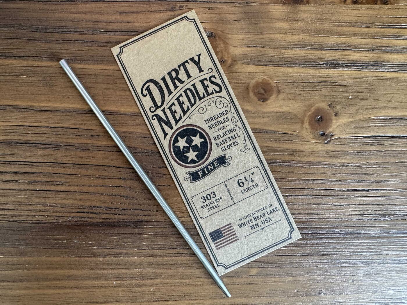 6¼ inch fine threaded relacing needle beside its kraft Dirty Needles card